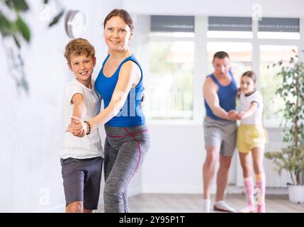 Glückliche Mutter und Sohn, die zusammen mit anderen Familienmitgliedern Tanzen üben Stockfoto