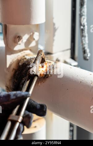 Der Arbeiter verbindet Metall mit einem Schweißbrenner, wodurch Funken und Wärme entstehen Stockfoto