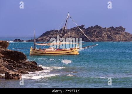 Ein traditionelles hölzernes Segelboot vor der felsigen Küste von Cadaques, Katalonien, Spanien Stockfoto