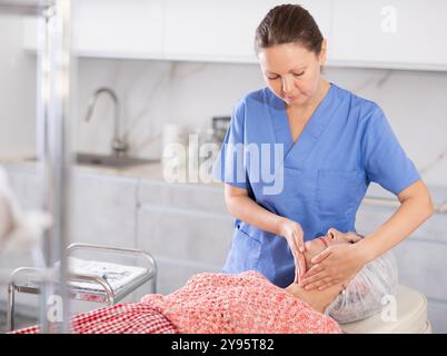 Erfahrener Arzt, der eine Gesichtsmassage an einen Reifen Patienten durchführt Stockfoto