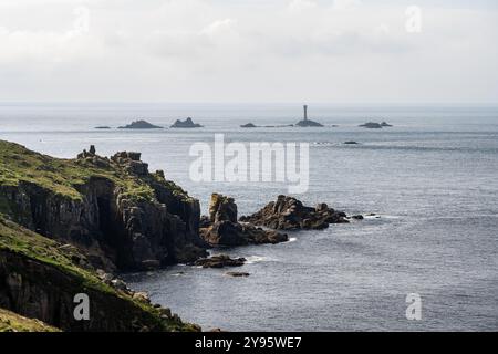 Die Sonne scheint auf den Klippen am Land's End von Cornwall, mit Langlauffelsen in der Ferne. Stockfoto