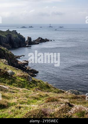 Die Sonne scheint auf den Klippen am Land's End von Cornwall, mit Langlauffelsen in der Ferne. Stockfoto