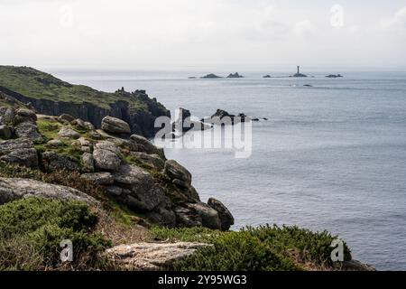 Die Sonne scheint auf den Klippen am Land's End von Cornwall, mit Langlauffelsen in der Ferne. Stockfoto