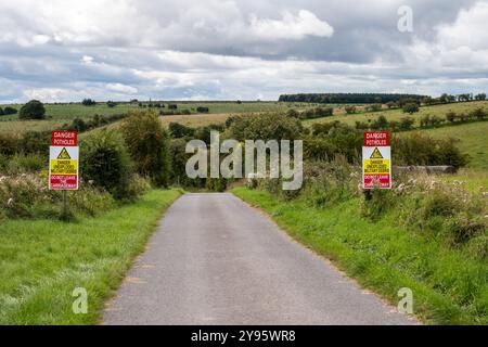 Schilder warnen vor nicht explodierten militärischen Trümmern auf einer Straße durch die Imber Range, einem Trainingsgebiet der britischen Armee in der Salisbury Plain in England. Stockfoto