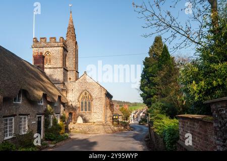 Shun glänzt in traditionellen strohgedeckten Hütten und der Pfarrkirche St. Osmund im Dorf Evershot, Dorset. Stockfoto