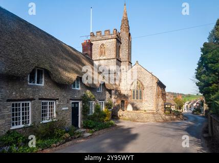 Shun glänzt in traditionellen strohgedeckten Hütten und der Pfarrkirche St. Osmund im Dorf Evershot, Dorset. Stockfoto