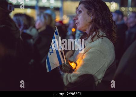 Toronto, Kanada. Oktober 2024. Ein Teilnehmer hält eine israelische Flagge und zündet eine Kerze während der Demonstration auf dem Sherman Campus an. Jüdische Gemeinden auf der ganzen Welt markierten den 7. Oktober, den tödlichsten Tag für das jüdische Volk seit dem Holocaust. Die UJA (United Jewish Appeal) Federation organisierte die Veranstaltung „7. Oktober: Marking One Year“ in Toronto, Kanada mit Gemeindemitgliedern, Verbündeten und Angehörigen von Geiseln, um Geschichten zu teilen, Kerzen anzuzünden und zusammen zu stehen, um die Ermordeten zu betrauern und die Überlebenden zu ehren. (Foto: Shawn Goldberg/SOPA Images/SIPA USA) Credit: SIPA USA/Alamy Live News Stockfoto