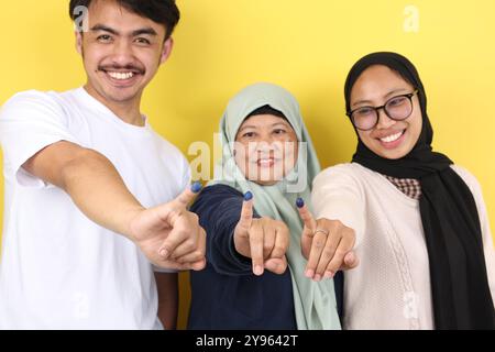 Die drei indonesische Familie zeigte Tinta Pemilu auf gelbem Hintergrund, nachdem sie für die Parlamentswahlen oder Pilkada gestimmt hatte Stockfoto