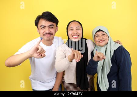 Die drei indonesische Familie zeigte Tinta Pemilu auf gelbem Hintergrund, nachdem sie für die Parlamentswahlen oder Pilkada gestimmt hatte Stockfoto