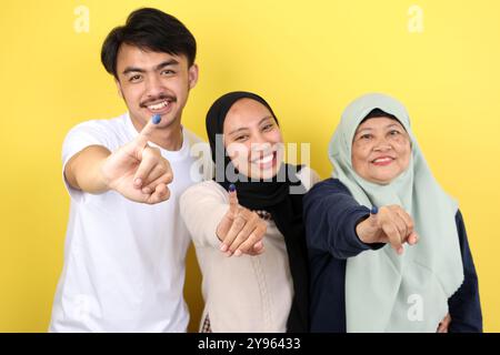 Die drei indonesische Familie zeigte Tinta Pemilu auf gelbem Hintergrund, nachdem sie für die Parlamentswahlen oder Pilkada gestimmt hatte Stockfoto