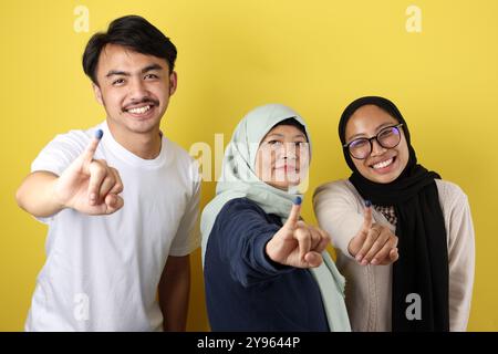 Die drei indonesische Familie zeigte Tinta Pemilu auf gelbem Hintergrund, nachdem sie für die Parlamentswahlen oder Pilkada gestimmt hatte Stockfoto