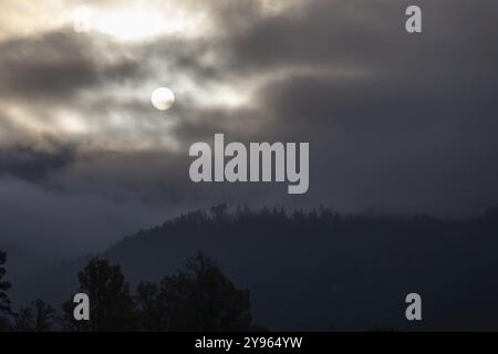 Sonne über einer Bergkette, die durch Morgenwolken und Nebel bricht, Leoben, Steiermark, Österreich, Europa Stockfoto