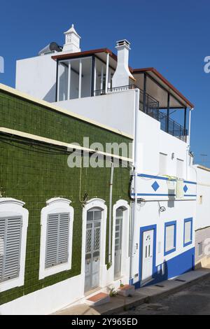 Modernes Haus mit grünen Fliesen und weißer Fassade. Balkone und Fenster, blauer Himmel im Hintergrund, Haus mit Azulejos, Fuseta, Fuzeta, Faro, Algarve Stockfoto