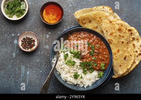 Traditionelles indisches Punjabi-Gericht Dal Makhani mit Linsen und Bohnen in schwarzer Schüssel serviert mit Basmati-Reis, Naan-Fladenbrot, frischem Koriander und Löffel o Stockfoto