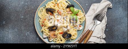 Italienische Meeresfrüchte-Pasta-Spaghetti mit Muscheln, Garnelen, Venusmuscheln in Tomatensoße mit grünem Basilikum auf Teller auf rustikalem blauem Betonhintergrund. Ich Stockfoto