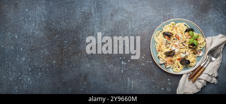 Italienische Meeresfrüchte-Pasta-Spaghetti mit Muscheln, Garnelen, Venusmuscheln in Tomatensoße mit grünem Basilikum auf Teller auf rustikalem blauem Betonhintergrund. Ich Stockfoto