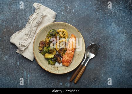 Köstliches Lachsfilet mit gegrillten Rosenkohl auf dem Teller, rustikaler Steinhintergrund, Draufsicht. Gesundes Abendessen mit gegrilltem Fisch und Gemüse, bal Stockfoto