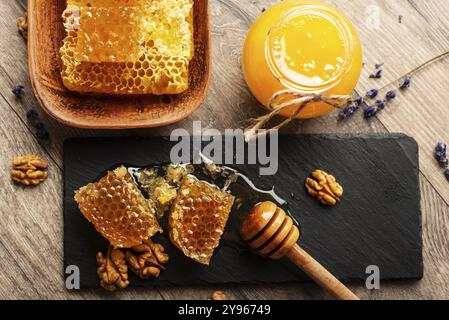 Honigwaben auf Schiefertablett mit Honig und Nüssen auf Küchentisch, Lebensmittelfotografie, Lebensmittelfotografie Stockfoto