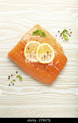 Frischer roher Lachs marmoriertes Filet auf weißem rustikalem Holztischhintergrund mit Zitrone, grobem Salz, grünen Kräutern von oben Blick. Gesundes Kochen und ausgewogene Diät Stockfoto