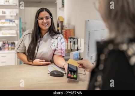 Rückansicht einer nicht erkennbaren Reifen Frau, die mit kontaktloser Technik in einer Apotheke bezahlt Stockfoto