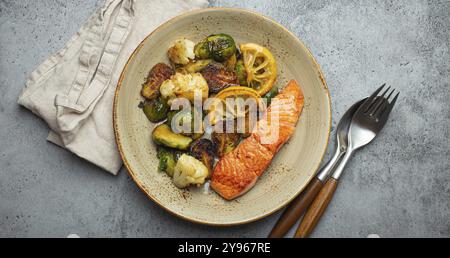 Köstliches Lachsfilet mit gegrillten Rosenkohl auf dem Teller, rustikaler Steinhintergrund, Draufsicht. Gesundes Abendessen mit gegrilltem Fisch und Gemüse, bal Stockfoto