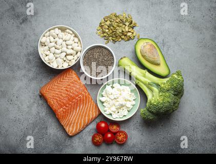 Auswahl gesunder Nahrungsmittel, wenn eine Person Diabetes hat: Lachsfisch, Brokkoli, Avocado, Bohnen, Gemüse, Seeds auf grauem Hintergrund von oben. Stockfoto