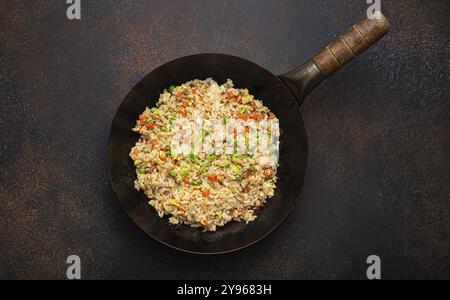 Authentischer chinesischer und asiatischer gebratener Reis mit Ei und Gemüse im Wok-Blick von oben auf rustikalem Betontischhintergrund. Traditionelles Gericht aus China, Lebensmittel ph Stockfoto