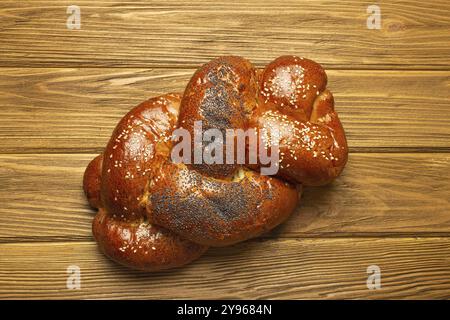 Frisch gebackenes Challah-Brot, bedeckt mit Mohn und Sesamsamen, Blick von oben auf rustikalen hölzernen Hintergrund, traditionelle festliche jüdische Küche, Essen Foto Stockfoto