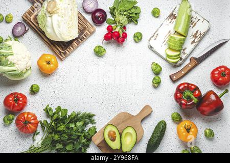 Frisches Gemüse mit Holzbrettern und Messer auf weißem Küchentisch. Kochen vegetarische Mahlzeit aus gesunden Zutaten, Diät Stockfoto