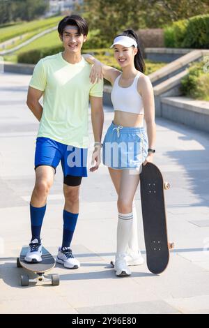 Glückliches junges Paar, das draußen Skateboarden macht Stockfoto