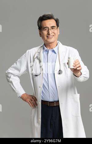 Leitender männlicher Arzt mit Pillenflasche Stockfoto