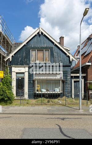 Ursprüngliches und traditionelles grünes Holzhaus in Zaandam. Schlecht gepflegt mit abblätternder Farbe. Stockfoto