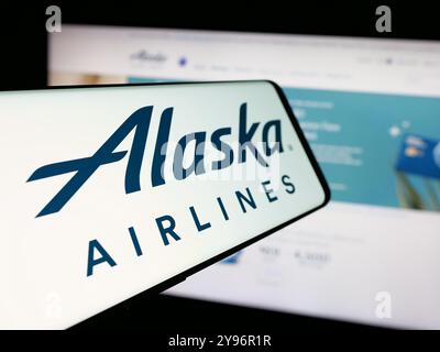 Cellphone with logo of American airline company Alaska Air Group Inc. on screen in front of website. Focus on center-left of phone display. Stock Photo