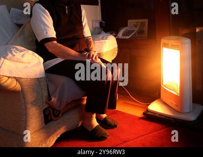 Aktenfoto vom 19./11/14: Ein generisches Stockfoto einer älteren Dame, die zu Hause in Liverpool sitzt und ihr elektrisches Feuer anliegt. Vier von fünf Rentnern, die unterhalb oder knapp über der Armutsgrenze leben, verlieren laut Benefizhilfemaßnahme UK die Winterkraftstoffzahlung im Rahmen geplanter Kürzungen. Ausgabedatum: Mittwoch, 9. Oktober 2024. Stockfoto