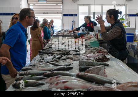 Costa Nova, Portugal - 11. September 2024: Kunden und Händler interagieren, während sie auf einem belebten Markt frische Meeresfrüchte auswählen. Stockfoto