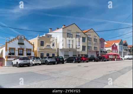 Costa Nova, Portugal - 11. September 2024 : Eine malerische Straße mit pulsierenden Gebäuden und geparkten Autos unter klarem blauen Himmel. Stockfoto