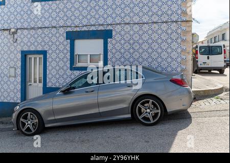 Costa Nova, Portugal - 11. September 2024 : Silbernes Auto parkt in der Nähe eines blau-weiß gekachelten Hauses in einer malerischen Nachbarschaft Stockfoto