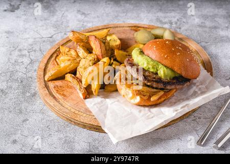 Burger mit karamelisierter Zwiebelsauce und Avocado auf einem Holzschneidebrett Stockfoto