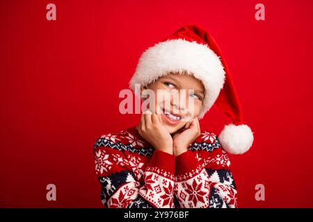 Foto-Porträt des charmanten kleinen Jungen aussehen traumhafter leerer Raum feiern weihnachten gekleidet gestrickter Pullover isoliert auf rotem Hintergrund Stockfoto