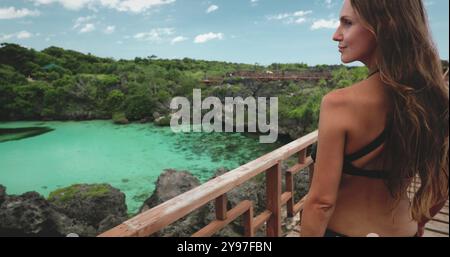 Eine Frau im Bikini steht auf einem Balkon mit Blick auf den Weekurri Lagoon Salt Lake auf Wild Sumba Island, Indonesien. Stockfoto