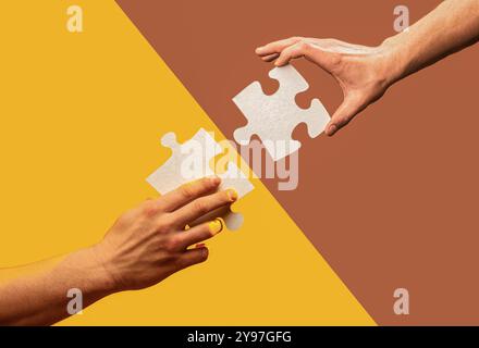 Zwei Puzzleteile ineinander greifen auf farbigem Hintergrund. Menschliche Hände halten, Puzzleteile zusammenstellen. Zwei Hände versuchen, ein Paar zu verbinden Stockfoto