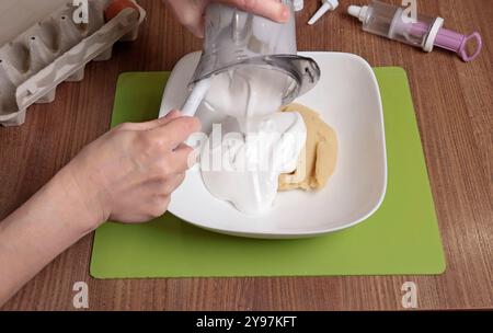 Teigzubereitung. Frau mische Puderzucker, Mandelmehl und verschlagenes Eiweiß mit Silikonspachtel in einer Schüssel. Macarons zu Hause backen. Schließen Stockfoto