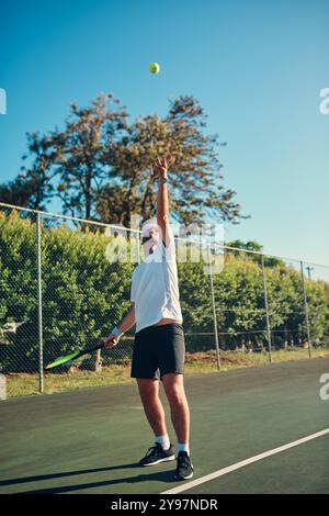 Mann, Tennis und Sport mit Ball in der Luft zum Servieren, Spielen oder Matchen auf dem Outdoor Court. Junge, männliche Person oder Athlet mit Schaukel im Training oder Stockfoto