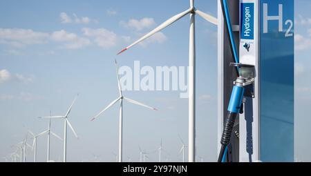 Wasserstofftankstelle mit Windturbinen im Hintergrund. Gewinnung von grünem Wasserstoff aus erneuerbaren Energiequellen. Stockfoto