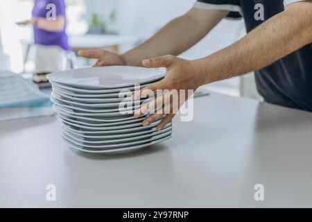 Nahaufnahme der Hände, die einen Stapel weißer Teller halten, bereit zum Servieren. Hochwertige Fotos Stockfoto