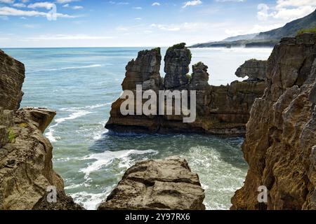 Wellen schlagen gegen dramatische Kalksteinfelsen, die in die Tasmanische See in Pancake Rocks, Punakaiki Village auf Südinsel, Neuseeland, auftauchen Stockfoto