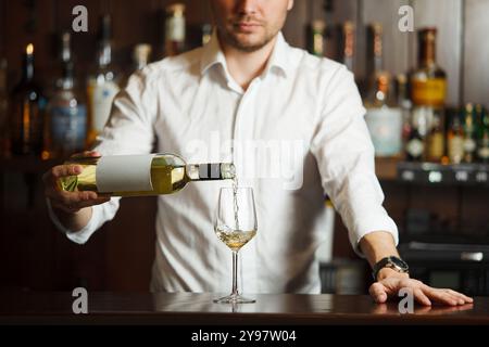 Sommeliermännchen gießt Weißwein in langstielige Weingläser. Stockfoto
