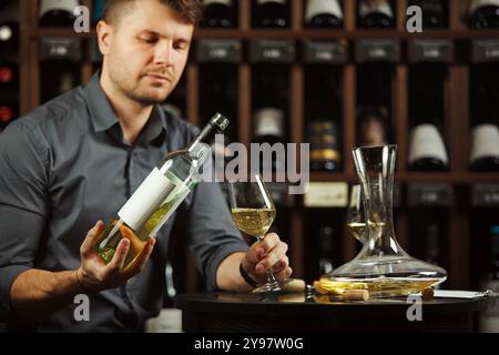 Sommelier gießt Weißwein aus der Flasche in Glas Stockfoto