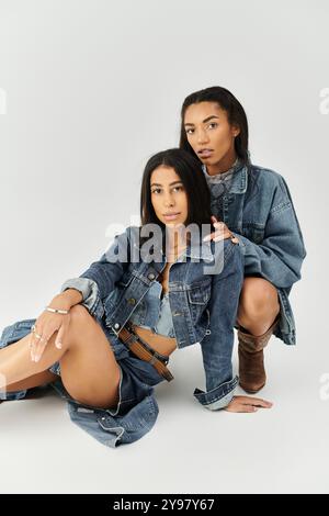 Zwei junge Frauen in trendigen Denim-Outfits strahlen Selbstbewusstsein und Stil aus, während sie gemeinsam posieren. Stockfoto