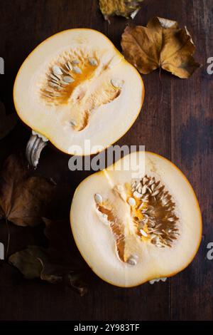 Rustikale Herbstatmosphäre: Ein frisch geschnittener Kürbis auf einem Holztisch, der das Kopfgeld der Saison in Erdtönen und organischen Texturen präsentiert. Stockfoto